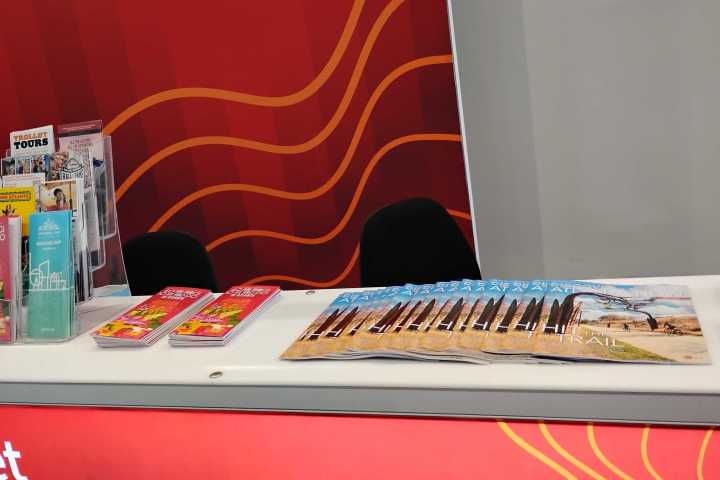 Brochures and flyers displayed on a table with a red wave background.