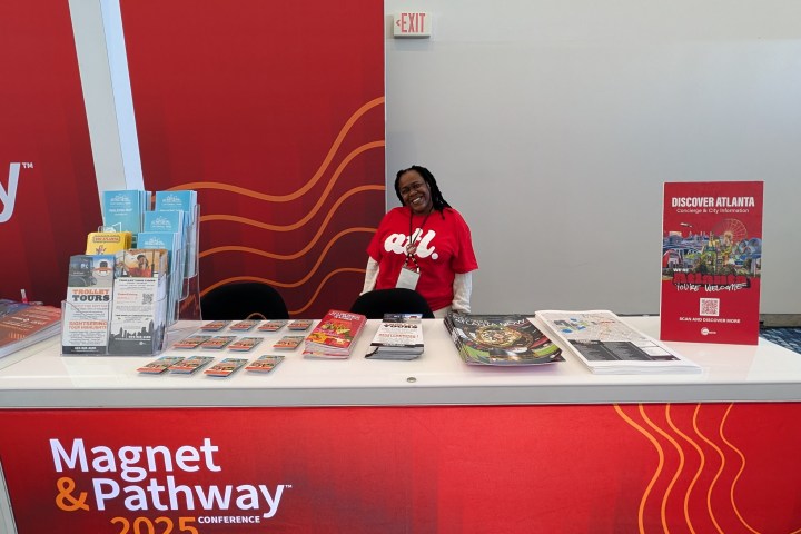 Exhibit booth for Discover Atlanta at Magnet & Pathway 2025 Conference with a smiling representative.